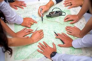 hands covering a map sales territory analyzed by a team